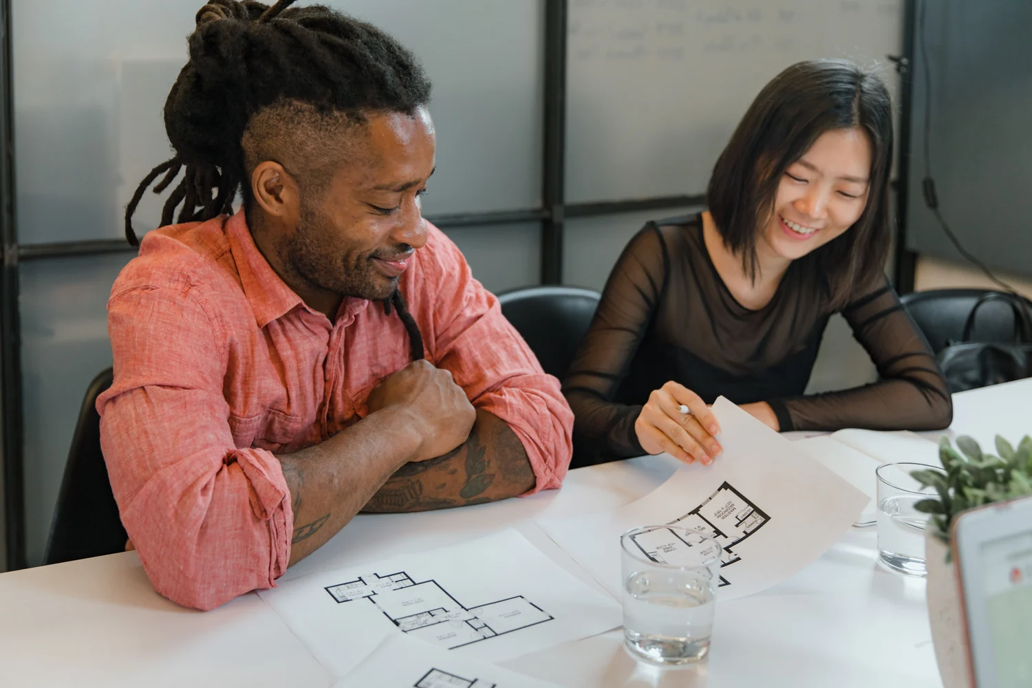 Two colleagues reviewing floor plans at a table.
